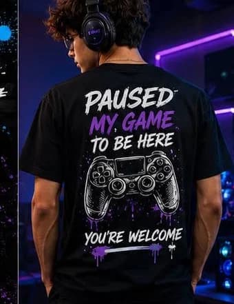 Man wearing a black t-shirt printed with a game controller design reading Paused My Game To Be Here